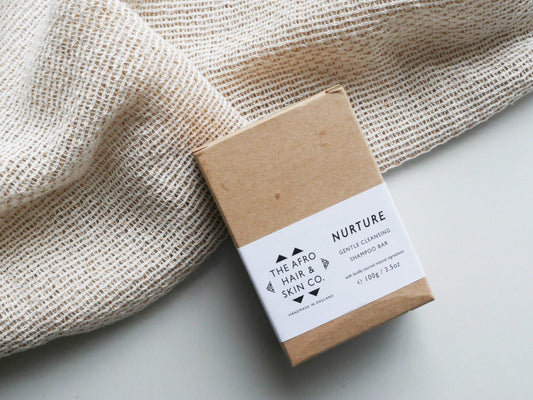 NURTURE - Gentle Cleansing Shampoo Bar in recycled cardboard box. On a neutral textured background. Afro hair shampoo for black hair. Afro hair products